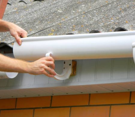 Rain gutter installation. Repair and renovate rain gutter pipeline on old house with asbestos rooftop.